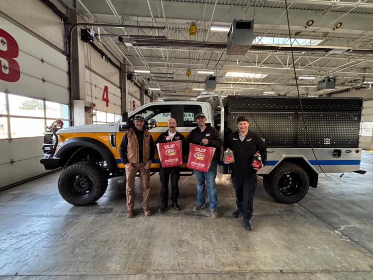 four guys sting in front of a fire truck