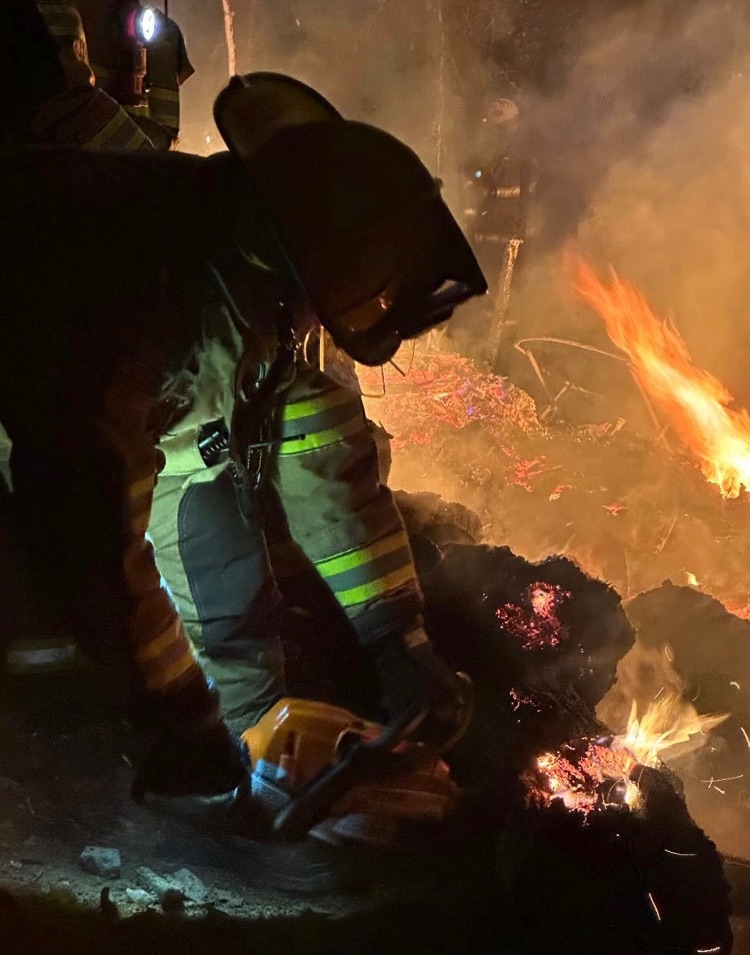 firefighter using a chain saw on a grass fire