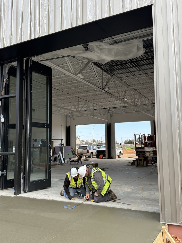 Two construction workers placing horse shoes in concrete