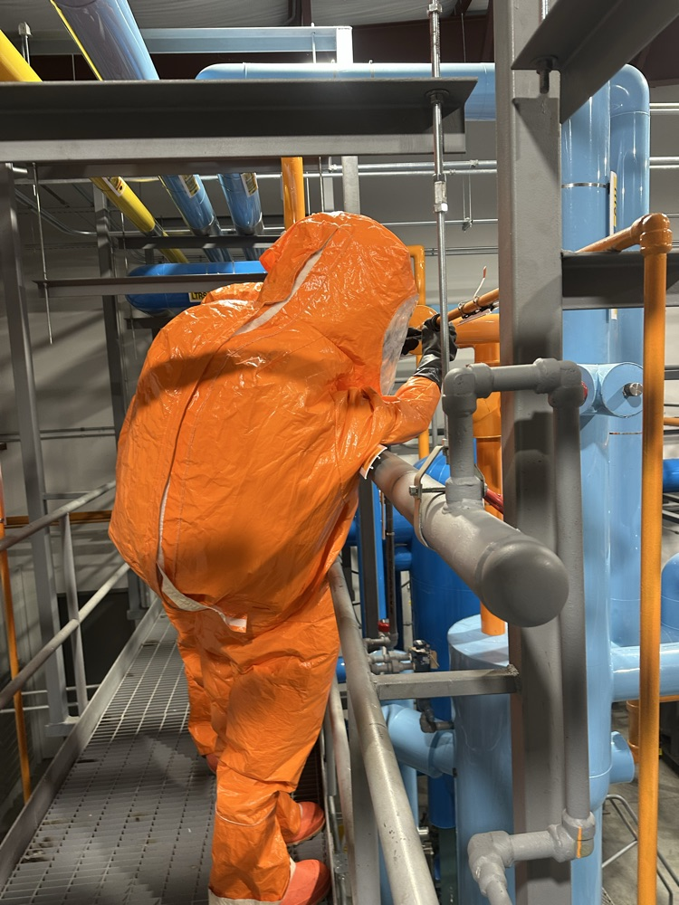 firefighter in a hazmat suit working to contain a leak for a drill