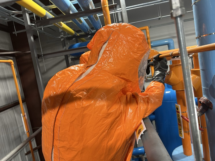 firefighter working in a hazmat suit to contain a leak