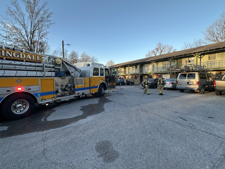 Firefighters waking infront of an apartment. with Ladder truck in background