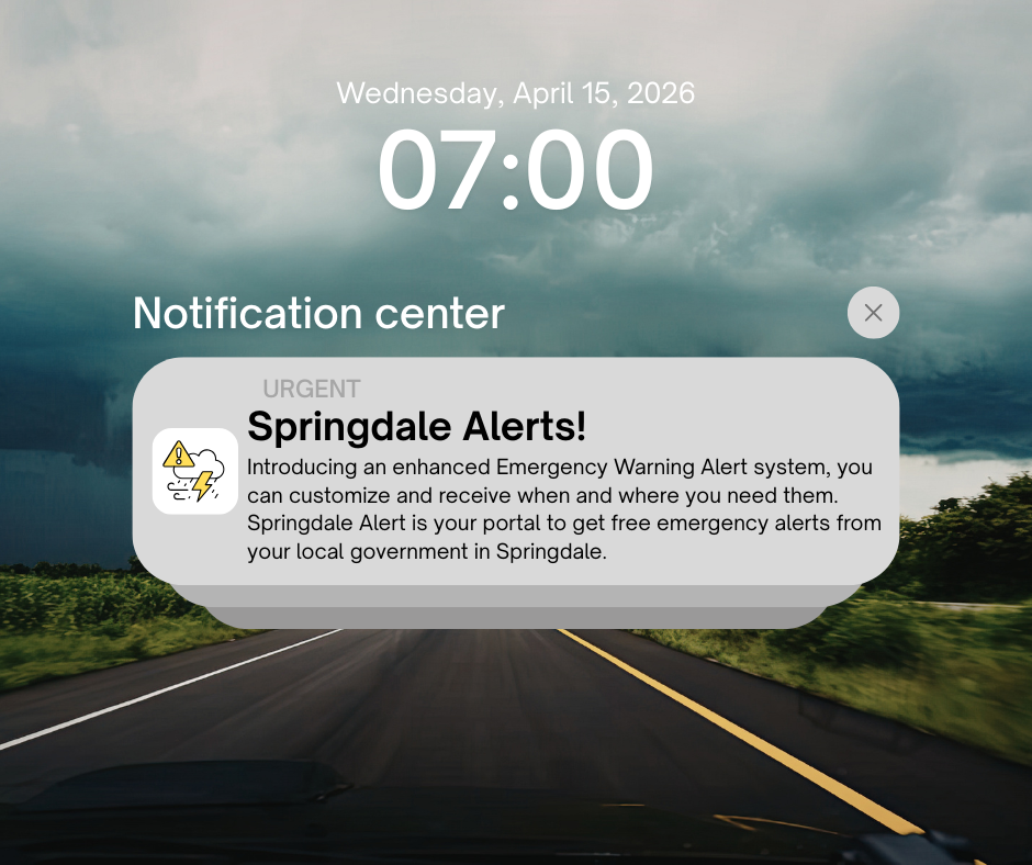 A mobile phone lock screen showing “Wednesday, April 15, 2026” at 7:00 AM with a stormy sky background over a road. A notification from “Springdale Alerts!” labeled urgent appears in the notification center, featuring a weather warning icon. The message promotes an enhanced emergency warning system, encouraging users to sign up to receive customizable local alerts from the Springdale government.