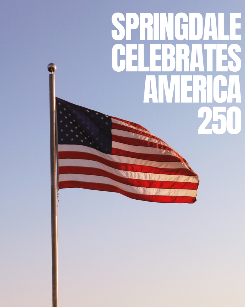 A tall flagpole stands against a clear, softly gradient sky, transitioning from pale blue at the top to a lighter, almost white tone near the horizon. At the top of the pole, a polished metallic finial reflects light. An American flag is fully unfurled and billowing to the right, its red and white stripes rippling in the wind and its blue field with white stars clearly visible. The sunlight catches the fabric, giving the flag a warm glow and emphasizing its movement and texture.  On the right side of the image, large, bold, white uppercase text reads “SPRINGDALE CELEBRATES AMERICA 250,” stacked in multiple lines. The composition places the flag to the left and the text to the right, creating a balanced, patriotic visual with a clean, minimal background that draws attention to both the flag and the celebratory message.