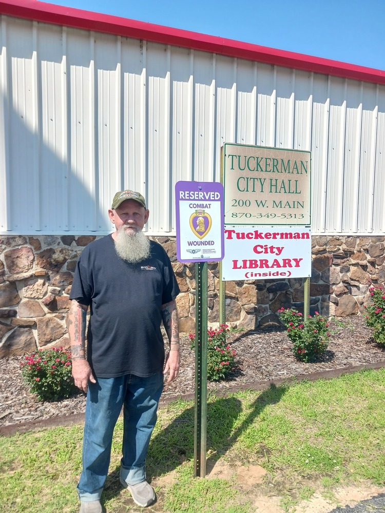 Wounded combat veteran sign, Mr. Birdsong posing by the sign.