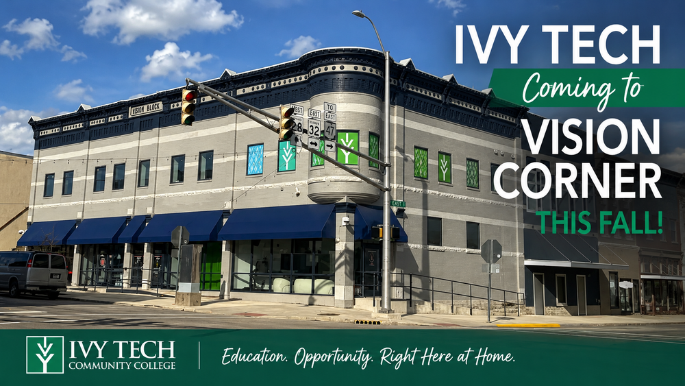 A wide view of the Vision Corner building on a sunny day, showing a two-story historic corner structure with blue awnings at a downtown intersection. Large overlay text reads “Ivy Tech Is Coming to Vision Corner This Fall!” in white and green lettering.