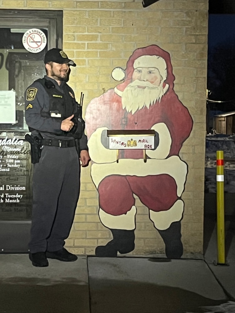 ACSD Officer Wieberg standing next to the wooden Santa cutout 