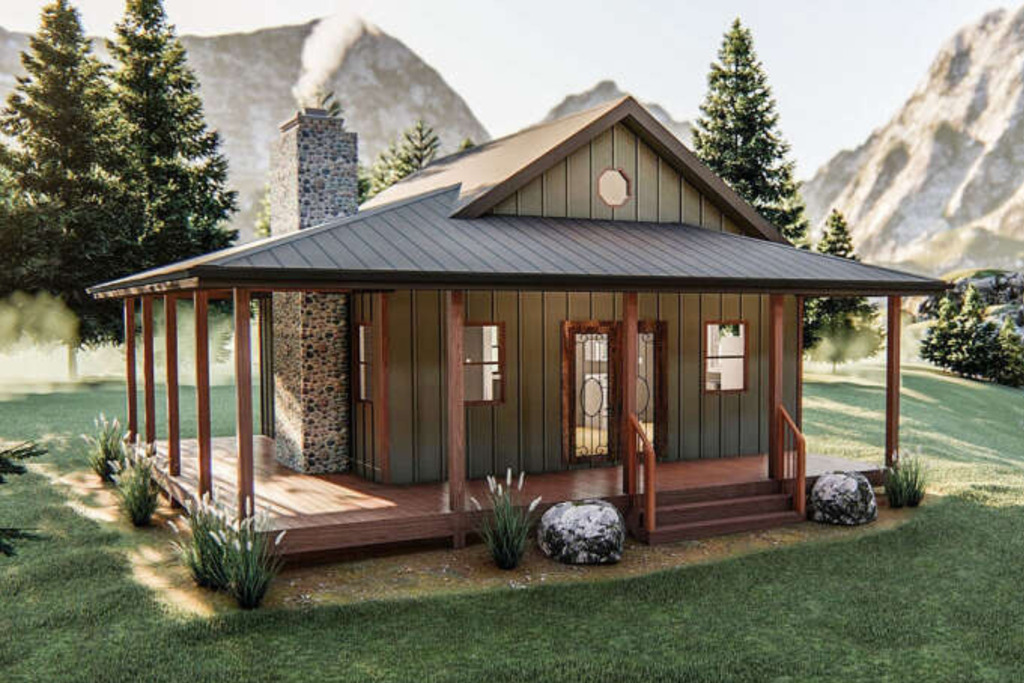 tiny house that is green in color with a dark brown tin roof, rock chimney, glass decorative door with a wrap around porch, wooden poles and landscaoing