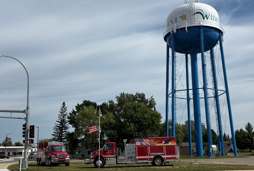 Two fire trucks sit outside the Wadena water tower, with a US flag flying at half staff, in honor of the fallen on 9/11