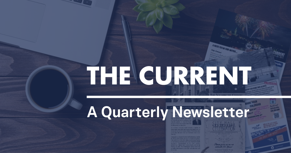 Desk with coffee laptop with text reading The Current, A Quarterly Newsletter