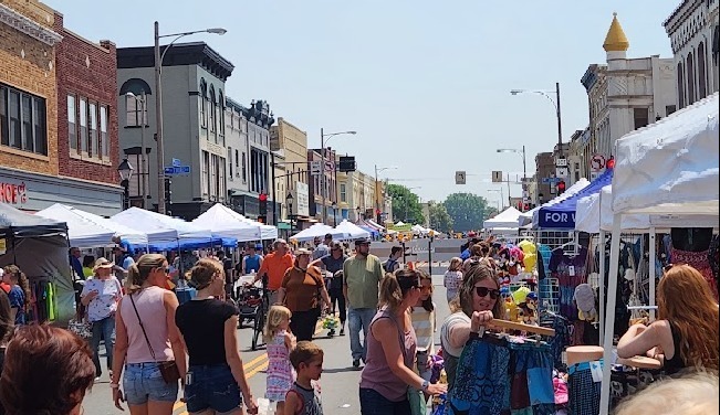 Watertown Main Street, blocked off to traffic, with vendor tents in the street and crowds of people shopping.