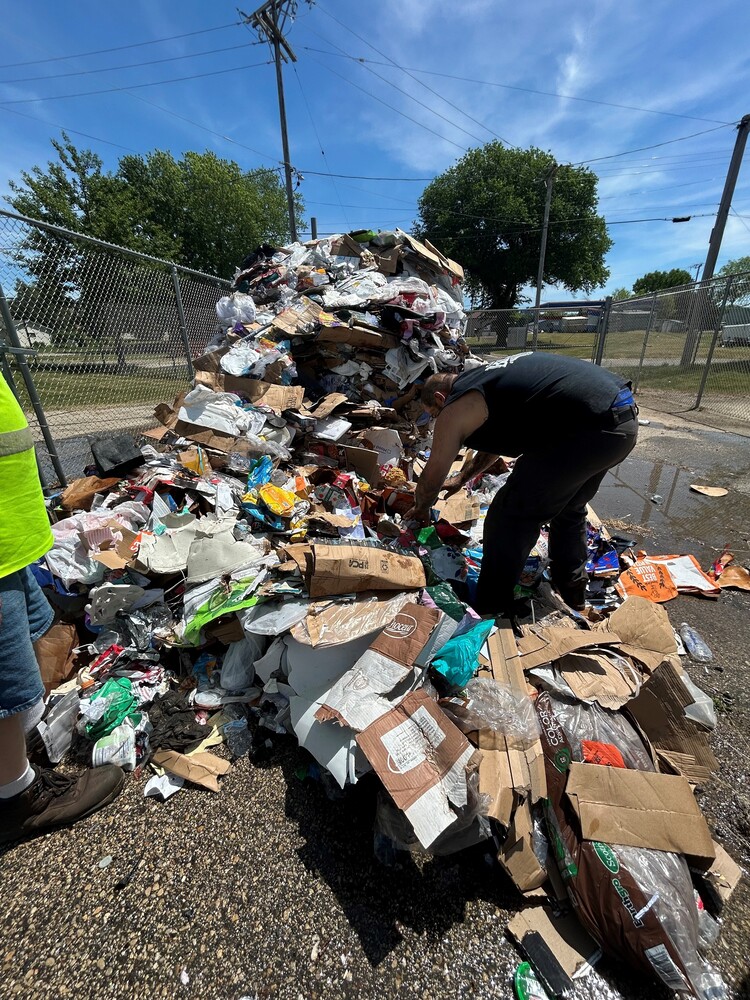 A man in sleeveless black shirt sirts through recyclable materials