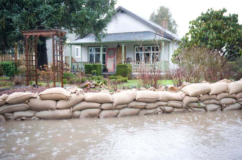 A house with sandbags stacked in front of it to prevent flood waters from entering.