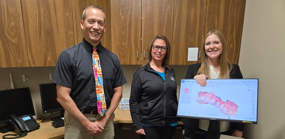 Mayor Stocks standing with Area Dental employees. One of the employees is holding a 3d scan of teeth.