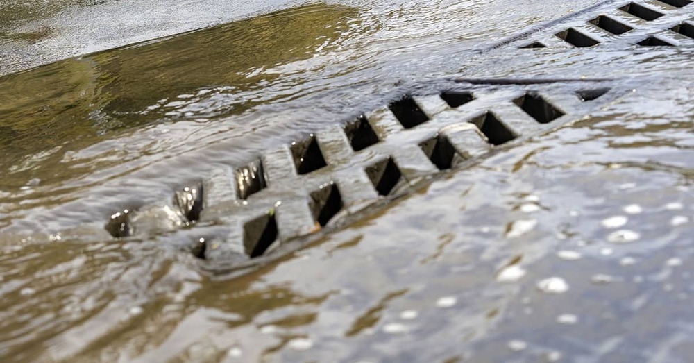 Close-up of a storm drain with water flowing in to it.