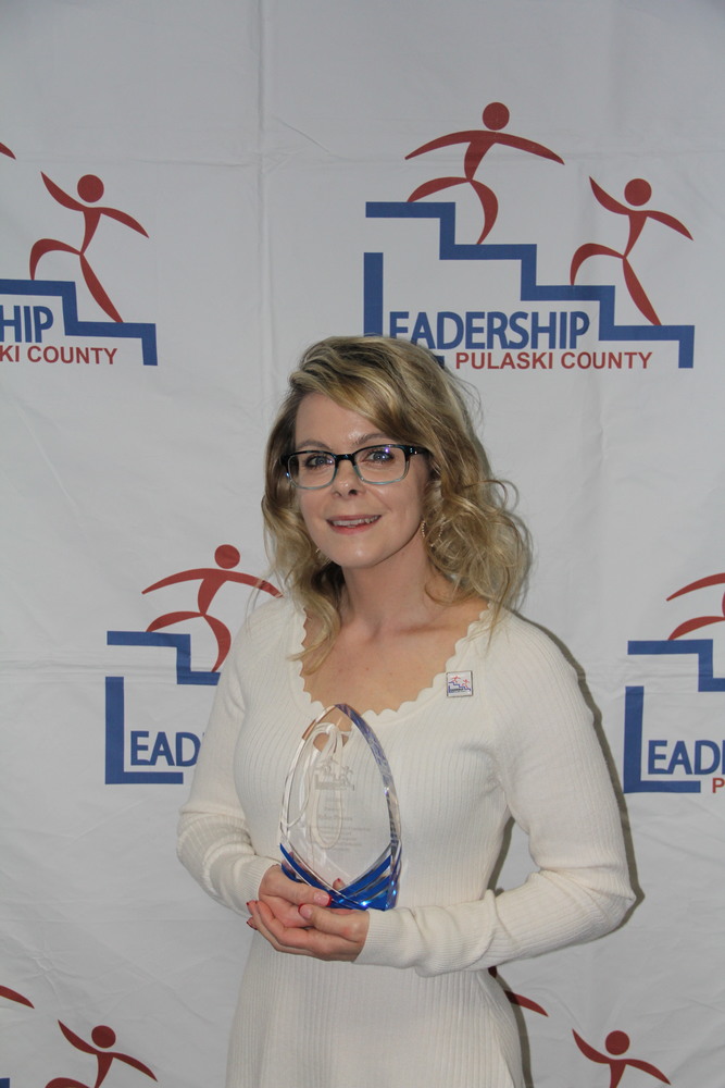 Kiley Powers standing in front of the Leadership Pulaski County logo, holding her graduation award.