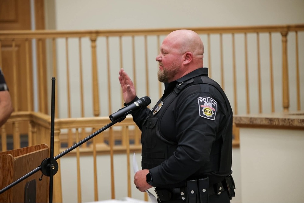 New Waynesville Police Chief Joshua Hazel raises his right hand as he takes the oath of office during the July 16, 2026, Waynesville City Council meeting, standing at a podium in his police uniform.