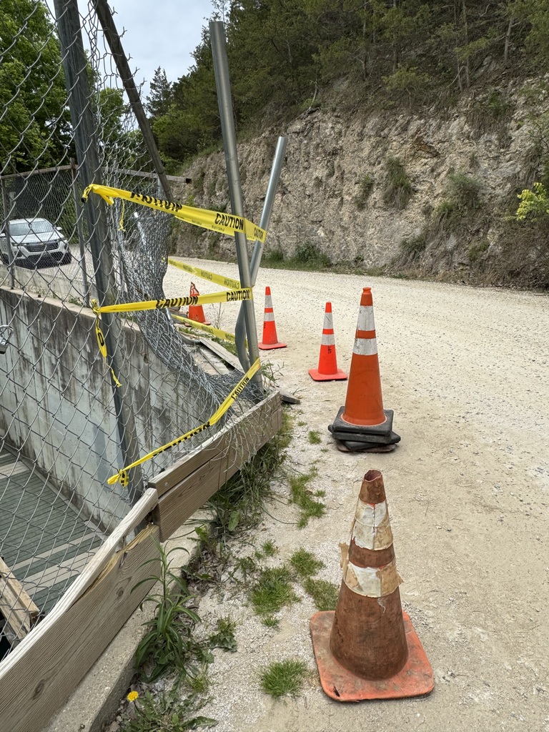 Photo of a dirt road (Superior Rd) showing damage to fencing and fencing poles. There is caution tape and orange cones indicating the area is marked off for safety and repairs.