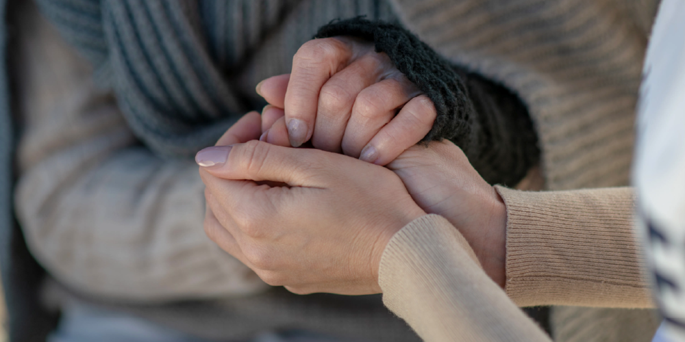 A picture of two people holding each others hands in comfort