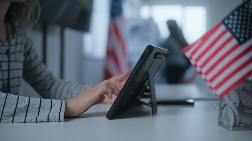 A person using an iPad next to small American flags