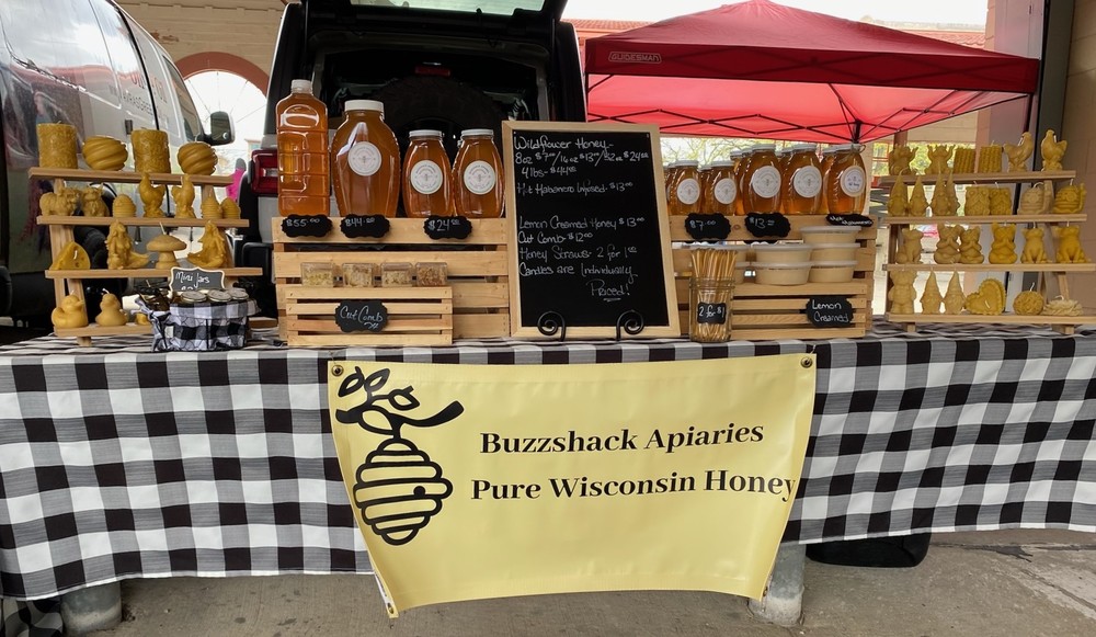 A photo of the Buzzshack Apiaries Pure Wisconsin Honey booth at the farmers market