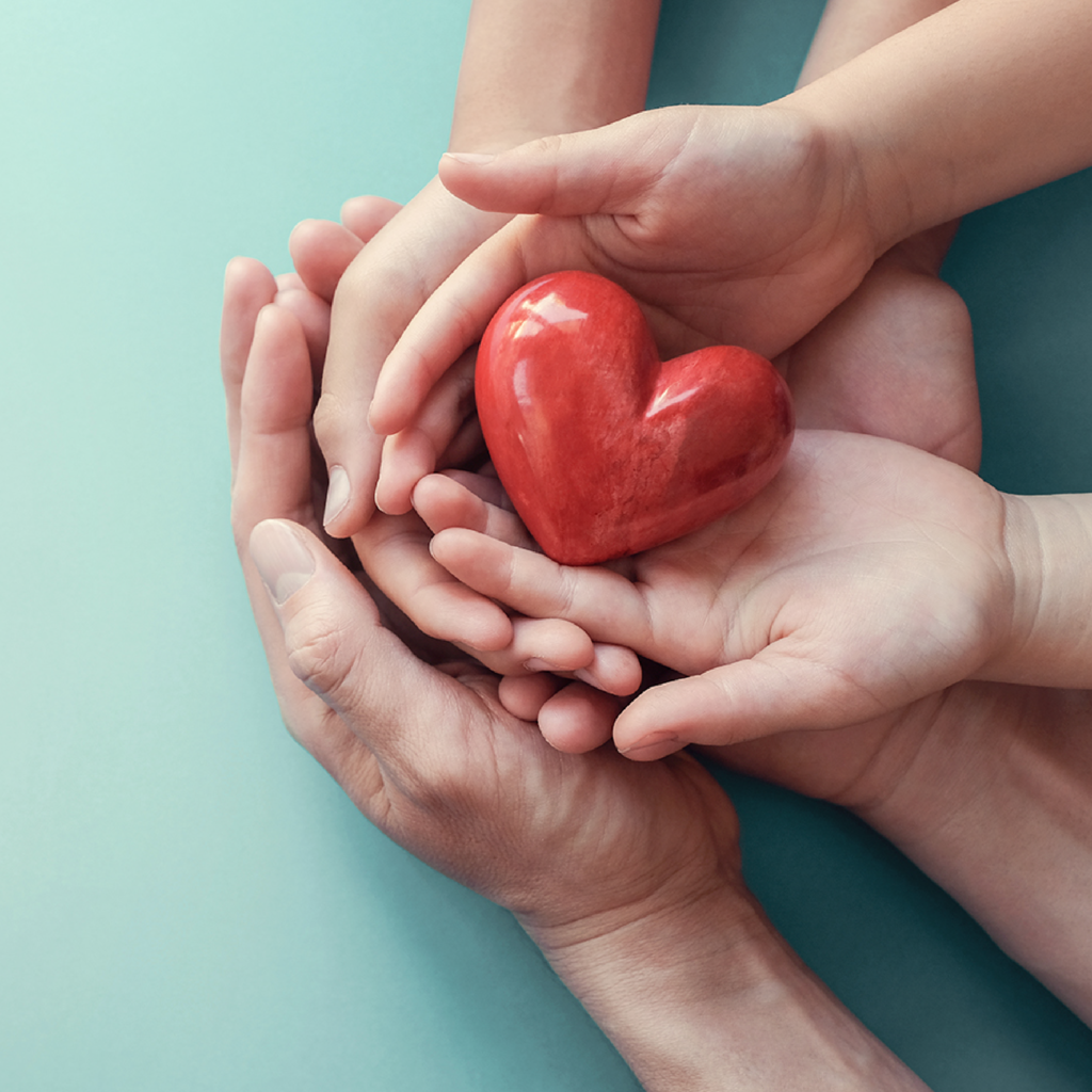 Three pairs of hands facing palm-up holding a heart figurine