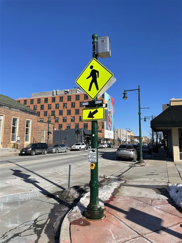 A photo of the intersection of 75th Street and Greenfield Avenue showing the pedestrian signal