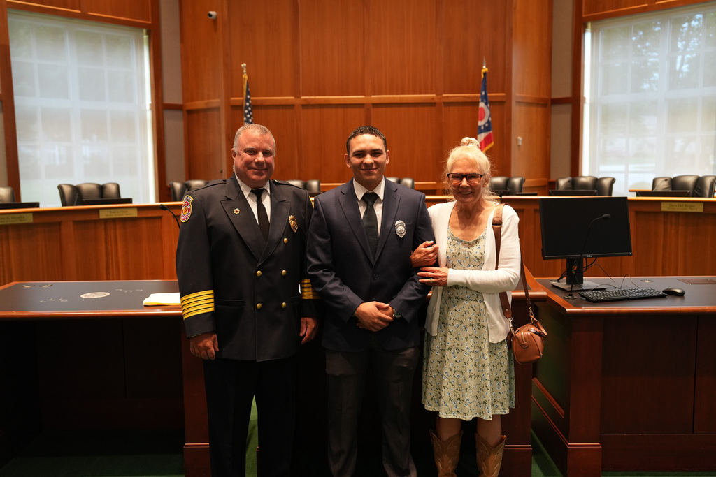 A new Westlake firefighter poses with the fire chief and a family member in Council Chambers after being sworn in