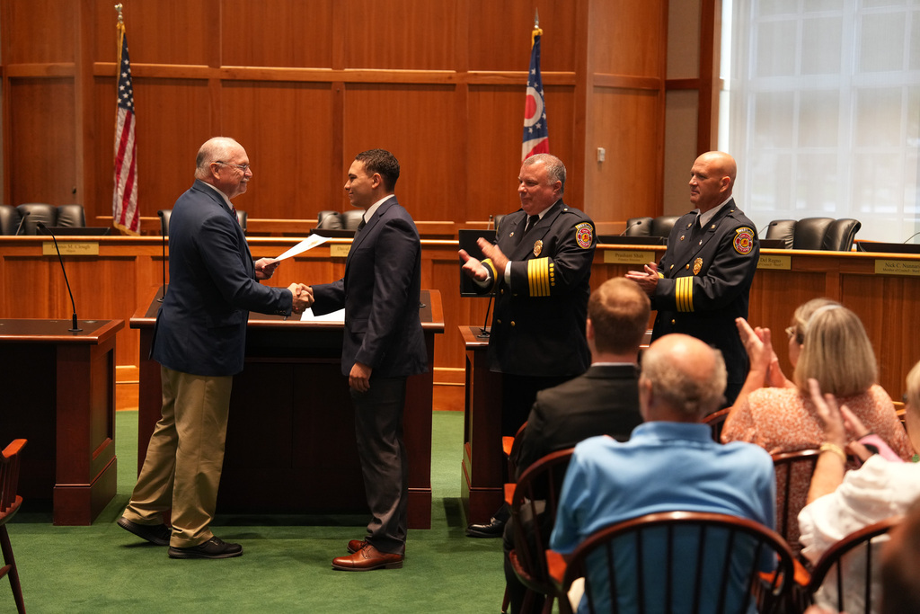 Mayor Clough shakes hands with a new Westlake firefighter during the swearing-in ceremony as fire chiefs applaud in Council Chambers