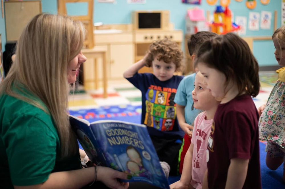 Teacher reading a book to young students