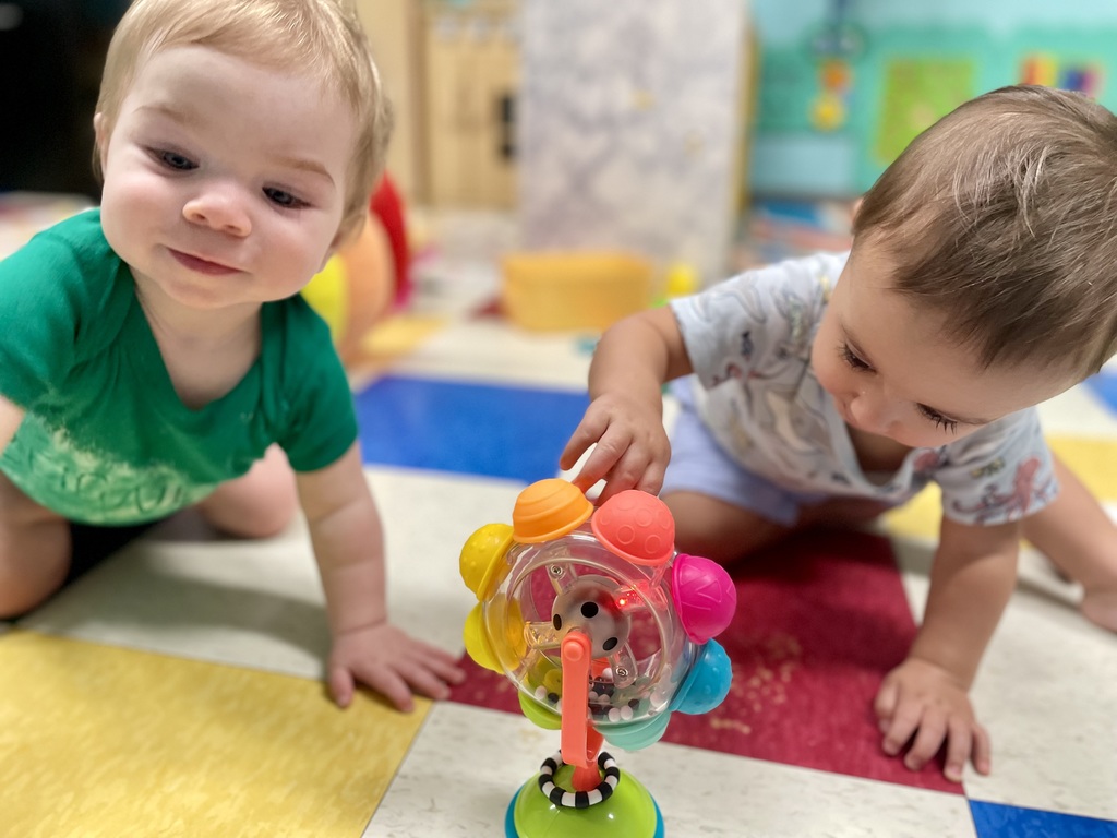 2 babies playing on the floor