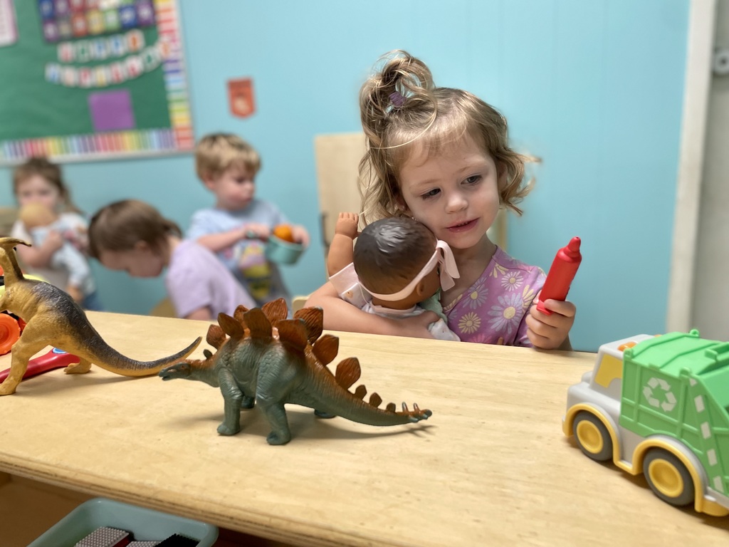 girl playing with toys and 3 other children in the background
