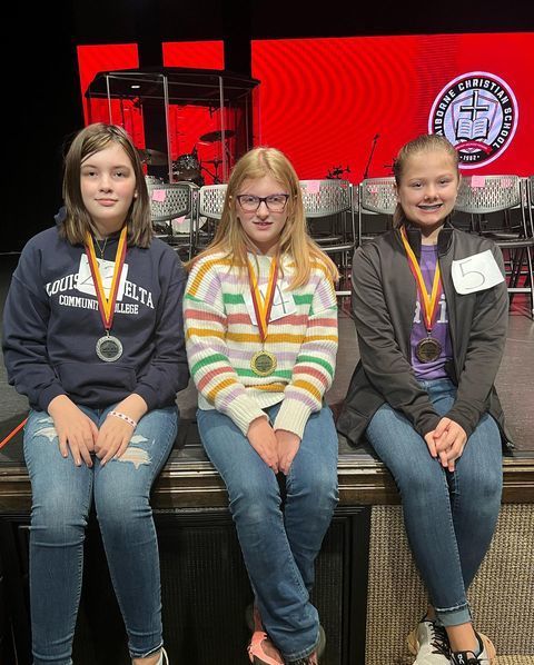 3 students smiling for group photo with medals