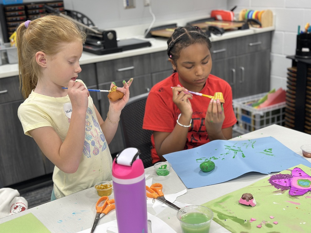 Two girls in Education Camp program painting pet rocks.