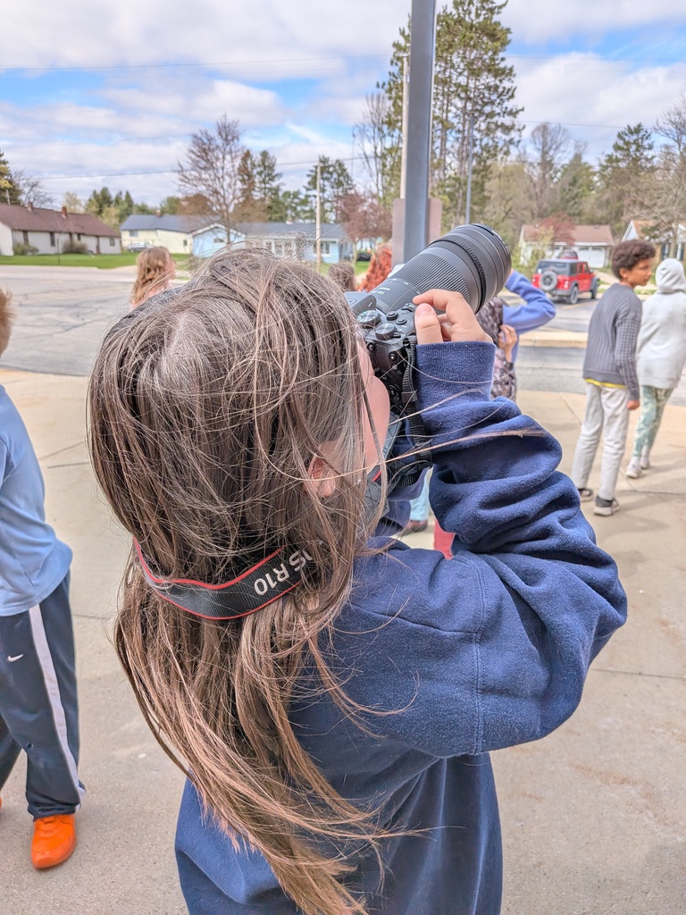 A student takes pictures of a drone in the air.