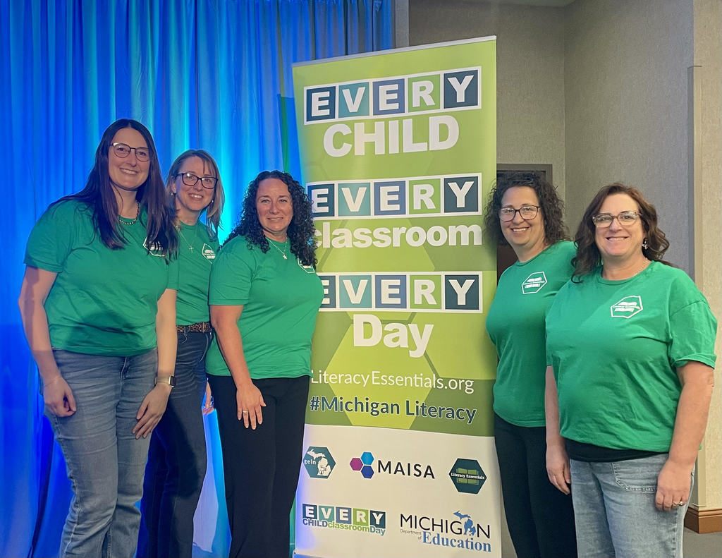 Five literacy coaches standing next to a sign that says, "Every Child, Every Classroom, Every Day."