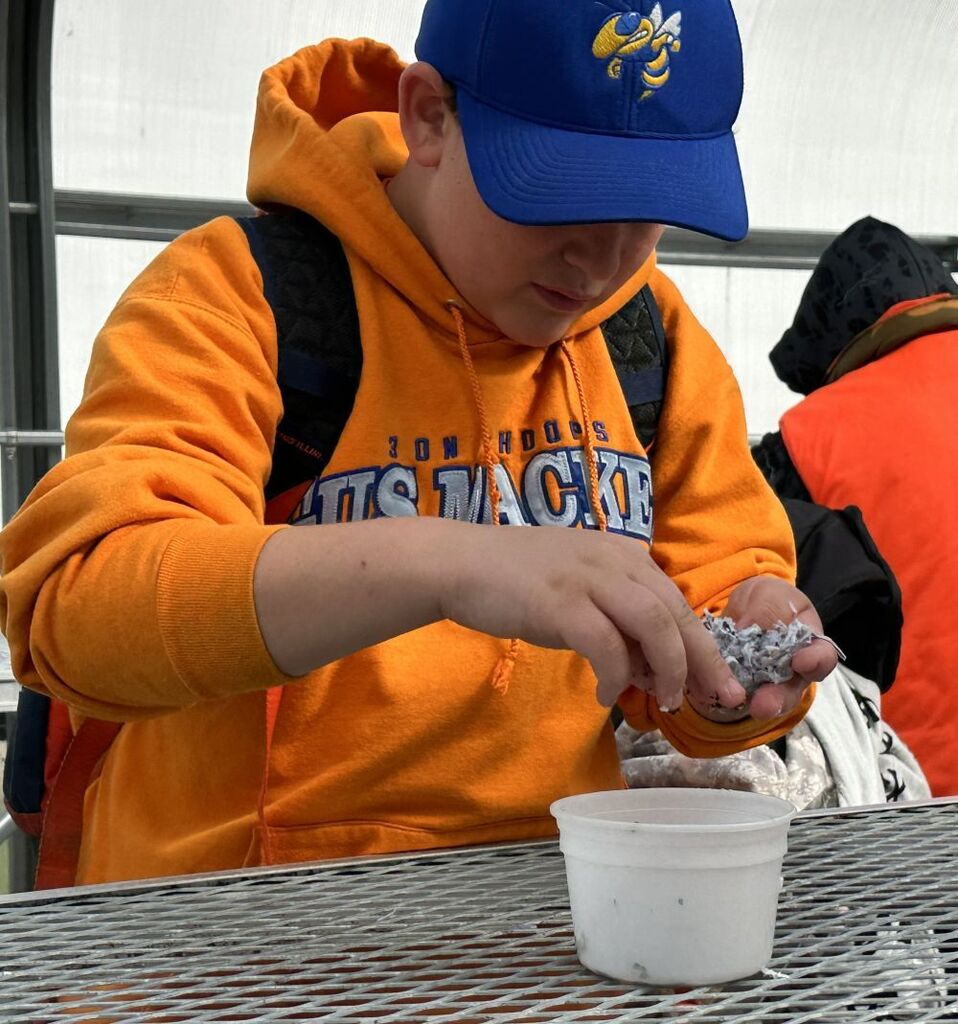 Student making a seed ball using shredded paper and seeds