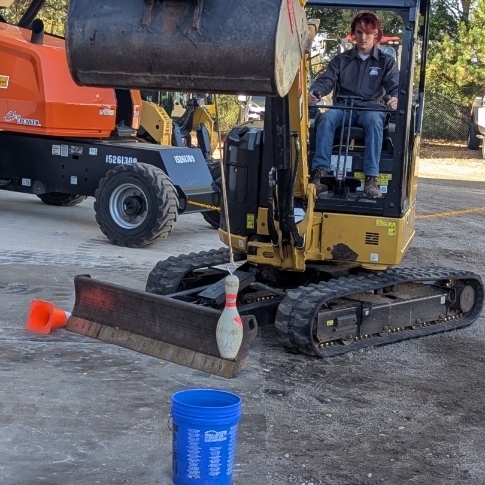 A student practices moving objects using heavy duty equipment 