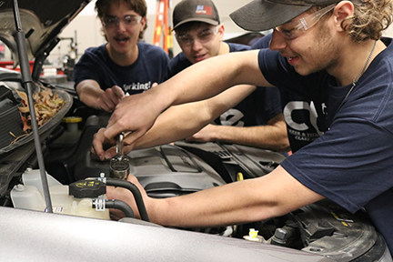 Students hands on working on car engine 