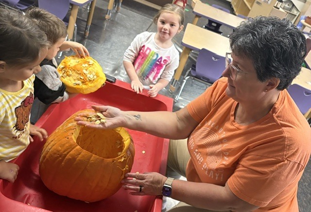 teacher and students exploring the inside of a pumpkin