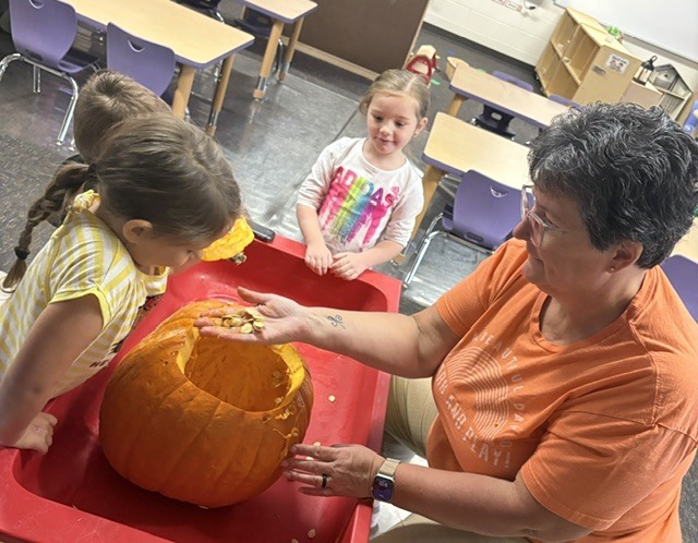 teacher showing pumpkin seeds to a student