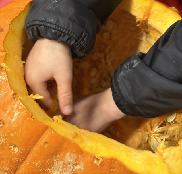 child's hands inside of pumpkin