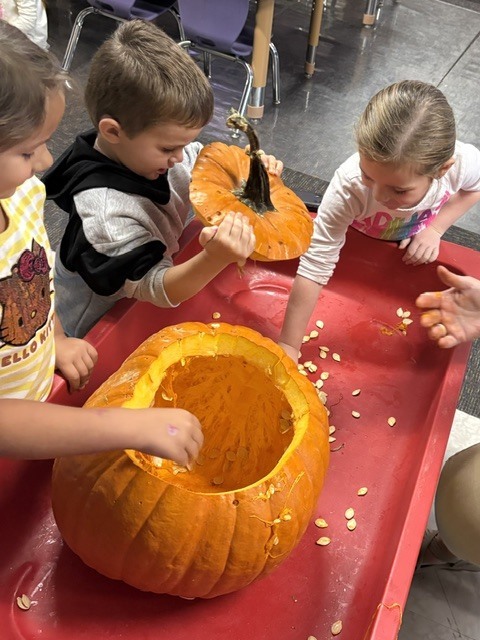 children scooping out the pumpkin with their hands