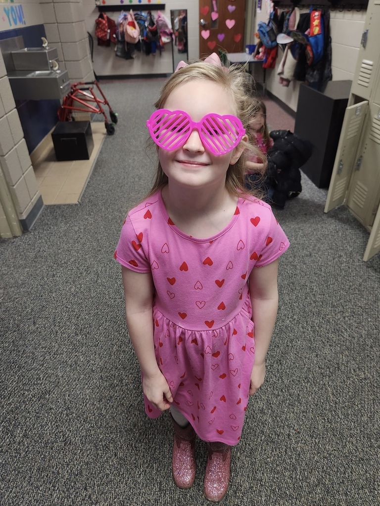 girl in all pink wearing pink heart shaped sunglasses smiling.