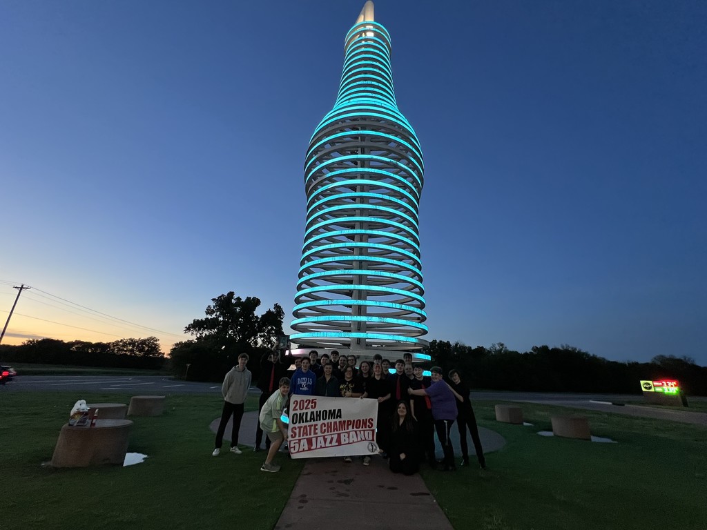 band members with state championship sign  in front of Pop sculpture 