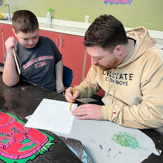 Art teacher working with student