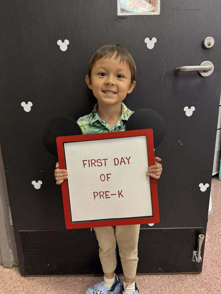 student holding first day of pre k sign 