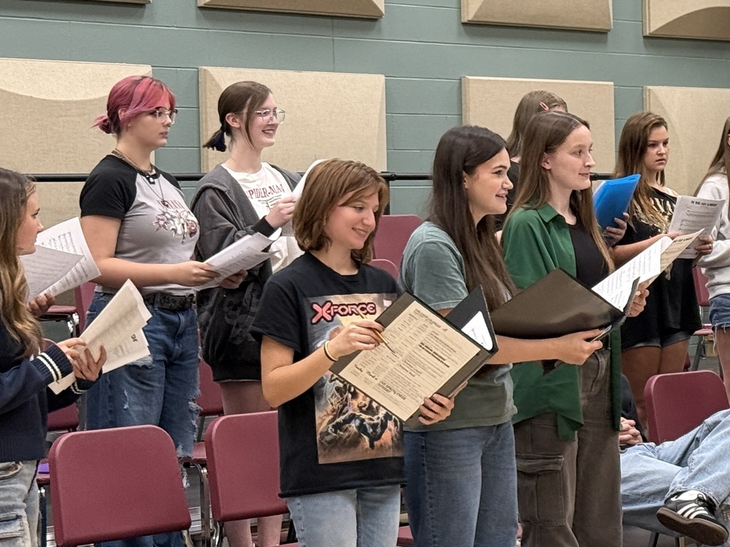 students smiling as they learn new music in choir
