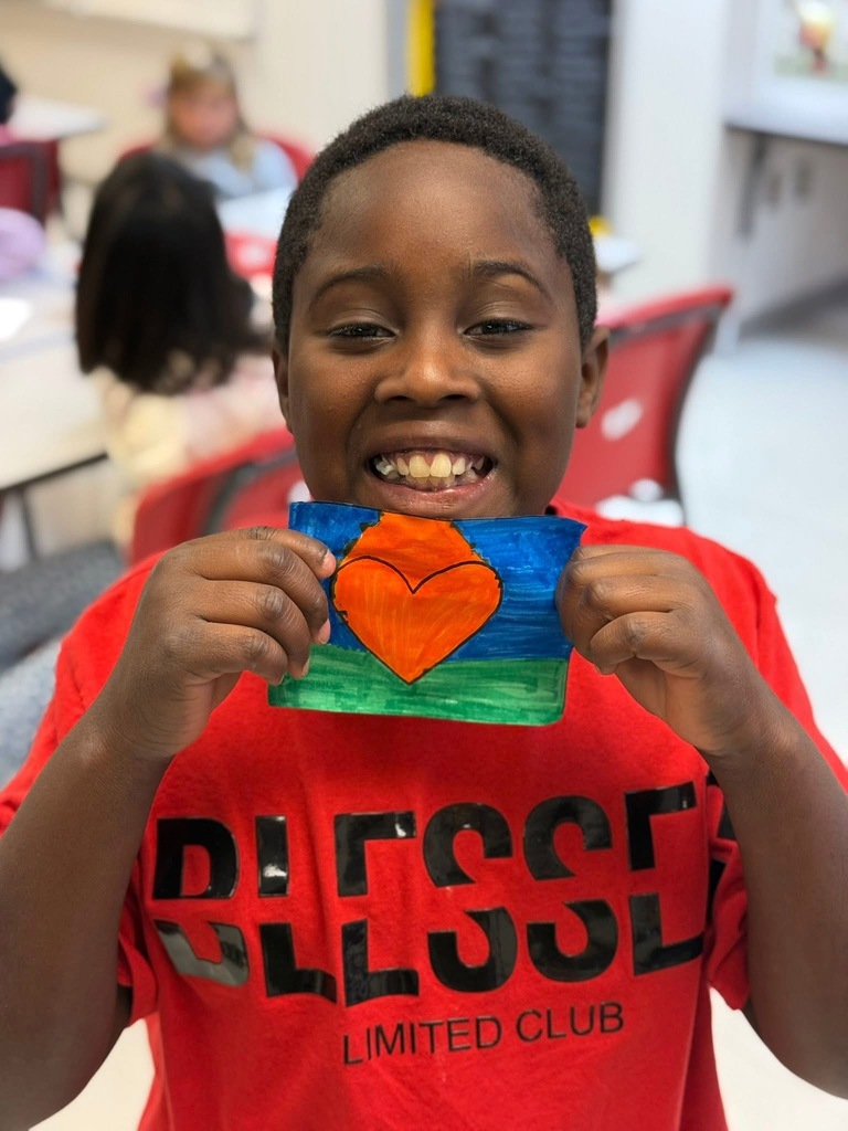 Student with big smile showing off his heart coloring