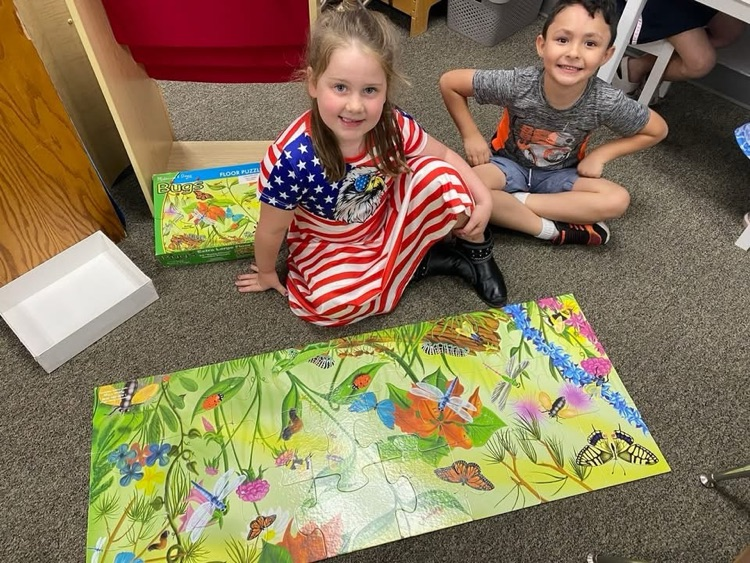 two students sitting on floor playing with puzzle